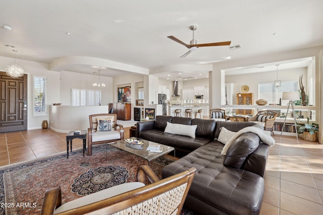 tiled living room featuring ceiling fan with notable chandelier