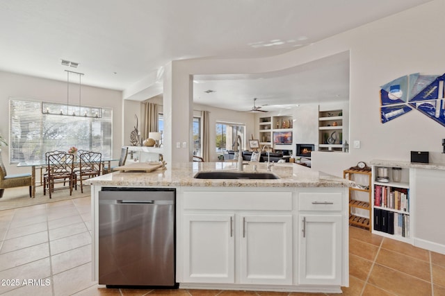 kitchen with built in features, dishwasher, sink, white cabinets, and hanging light fixtures