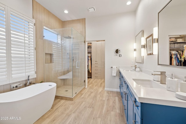 bathroom with vanity, wood-type flooring, and plus walk in shower