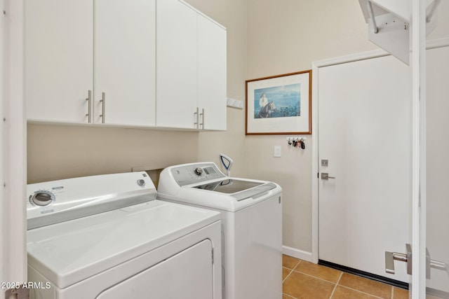 clothes washing area featuring cabinets, washing machine and dryer, and light tile patterned floors