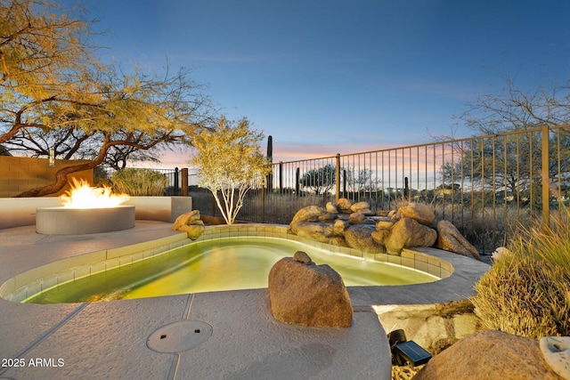 pool at dusk featuring an outdoor fire pit