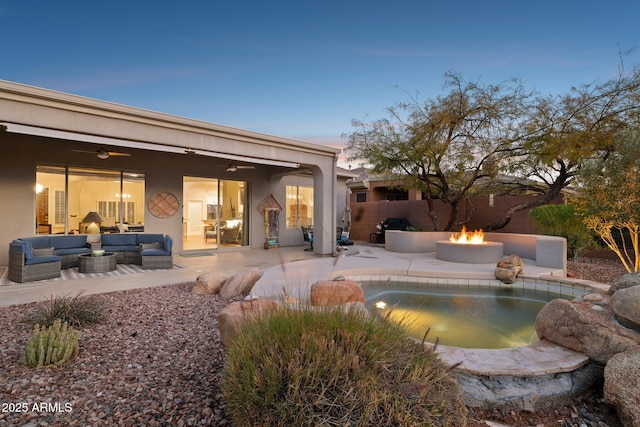 pool at dusk with an outdoor living space with a fire pit, a patio, and ceiling fan