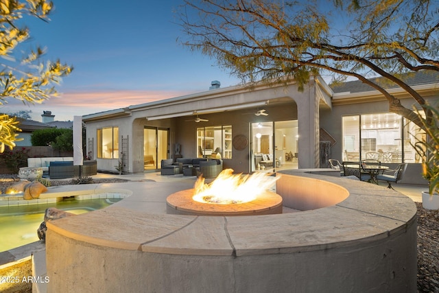 back house at dusk featuring a patio area, an outdoor living space with a fire pit, and ceiling fan