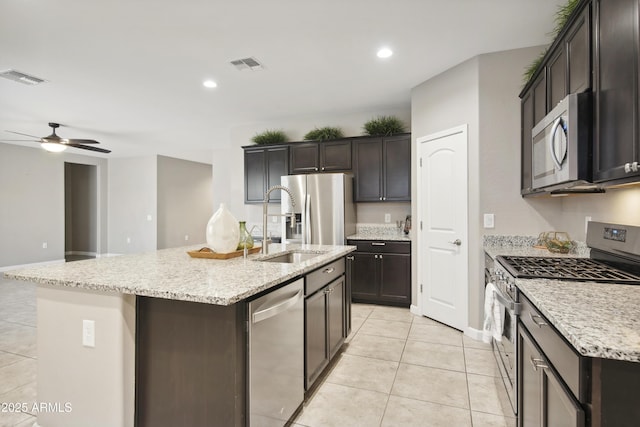 30776 W Earll Dr, Buckeye, AZ 85396 - kitchen with appliances with stainless steel finishes, light tile patterned floors, a ceiling fan, a kitchen island with sink, and light stone countertops