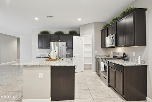 30776 W Earll Dr, Buckeye, AZ 85396 - kitchen featuring stainless steel appliances, light tile patterned flooring, light stone countertops, a kitchen island with sink, and recessed lighting