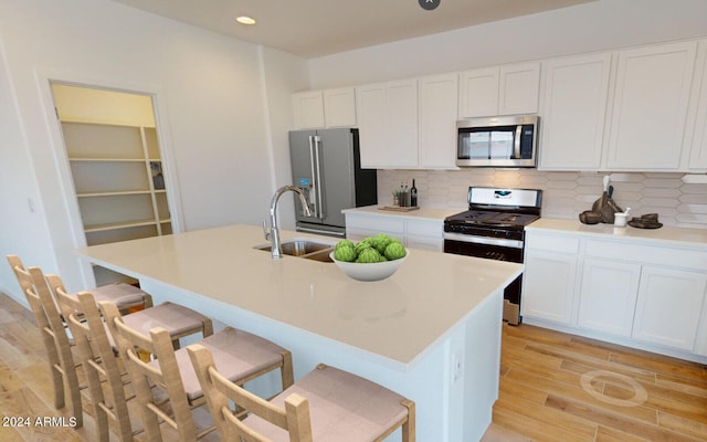 kitchen with a sink, white cabinets, a kitchen bar, and stainless steel appliances