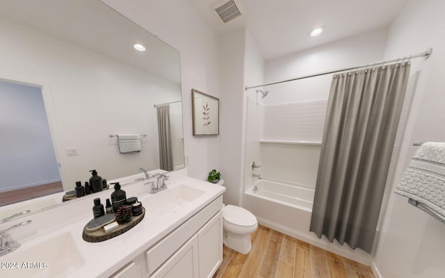 bathroom with visible vents, double vanity, shower / tub combo with curtain, toilet, and a sink