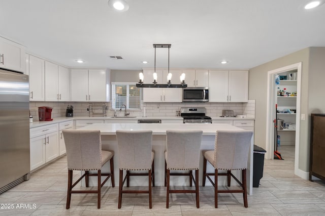 kitchen featuring a kitchen island, appliances with stainless steel finishes, sink, and pendant lighting