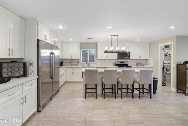 kitchen featuring white cabinetry, decorative light fixtures, a breakfast bar area, and stainless steel appliances