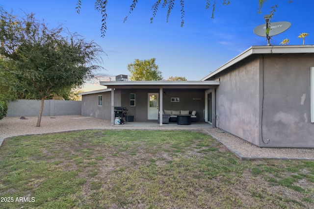 back of property with an outdoor living space, a patio, and a yard