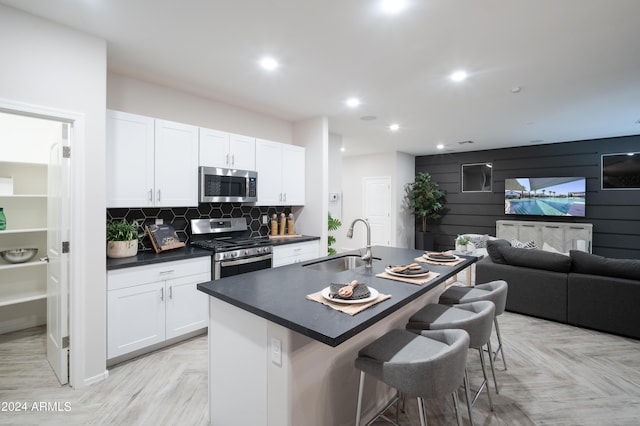 kitchen featuring dark countertops, a kitchen bar, decorative backsplash, appliances with stainless steel finishes, and a sink