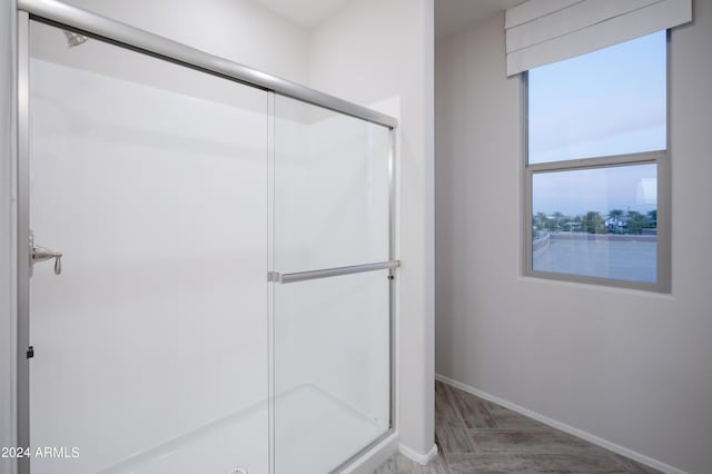 full bath featuring wood finished floors, baseboards, and a stall shower