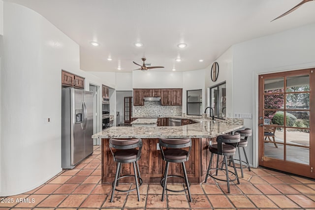 9035 W Villa Chula, Peoria, AZ 85383 - kitchen with ceiling fan, tasteful backsplash, light stone countertops, a peninsula, and stainless steel appliances