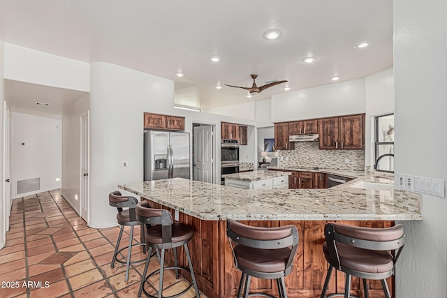 9035 W Villa Chula, Peoria, AZ 85383 - kitchen with appliances with stainless steel finishes, a kitchen breakfast bar, backsplash, under cabinet range hood, and visible vents