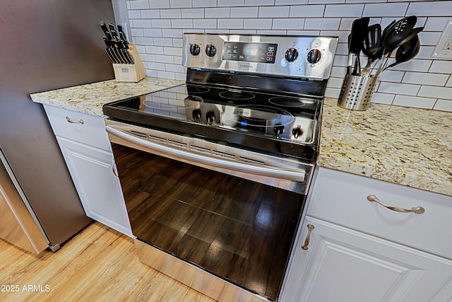 kitchen featuring white cabinetry, light stone counters, stainless steel appliances, light hardwood / wood-style floors, and decorative backsplash