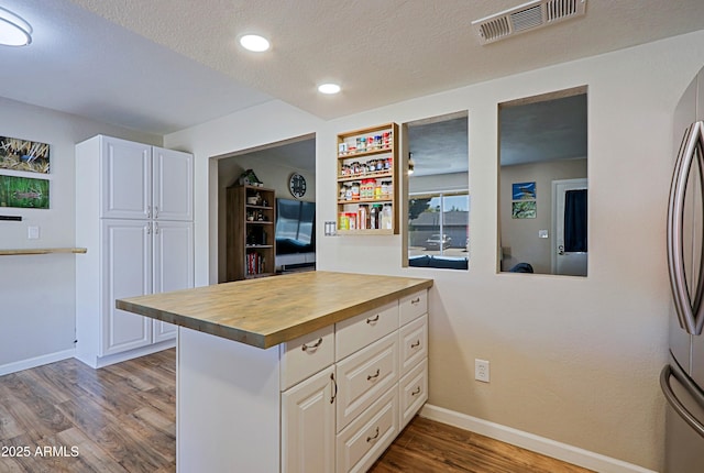 kitchen with white cabinetry, wood-type flooring, butcher block counters, and a textured ceiling