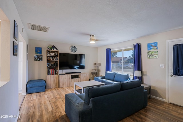 living room featuring ceiling fan, hardwood / wood-style flooring, and a textured ceiling