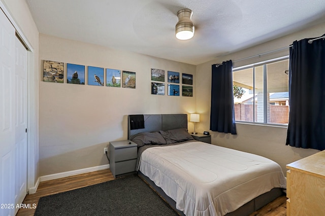 bedroom featuring dark wood-type flooring, ceiling fan, a closet, and a textured ceiling