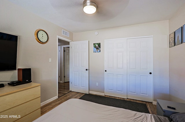 bedroom featuring dark wood-type flooring, a closet, and ceiling fan