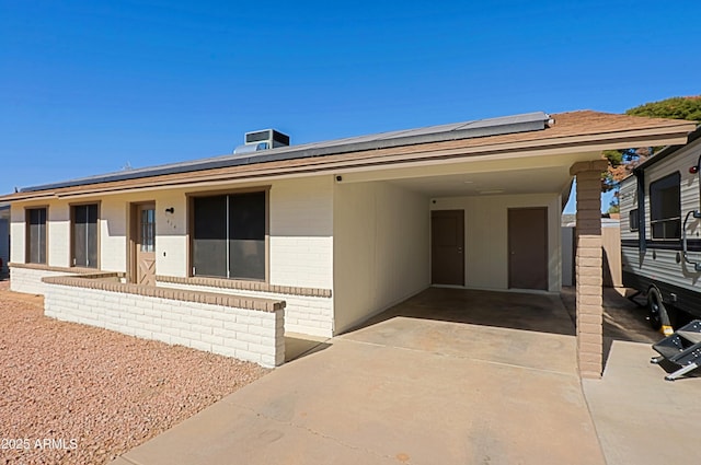 ranch-style house featuring cooling unit, a carport, and solar panels