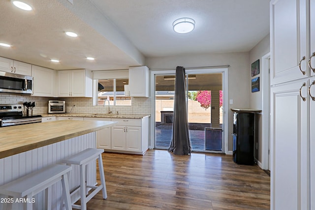 kitchen featuring white cabinetry, butcher block countertops, stainless steel appliances, and sink