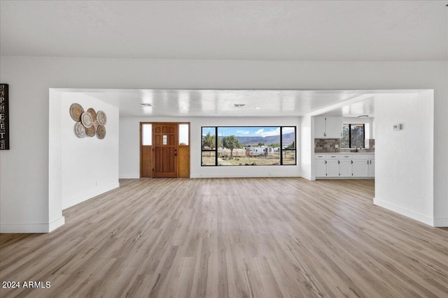 unfurnished living room featuring sink and light wood-type flooring