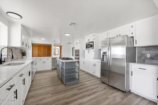 kitchen featuring sink, appliances with stainless steel finishes, a kitchen island, light hardwood / wood-style floors, and white cabinets