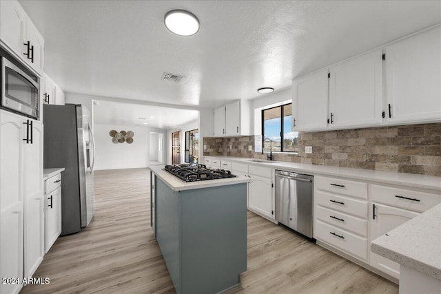 kitchen featuring a kitchen island, appliances with stainless steel finishes, sink, white cabinets, and light hardwood / wood-style flooring