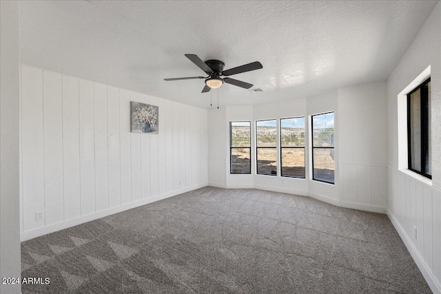 carpeted spare room featuring ceiling fan and a textured ceiling