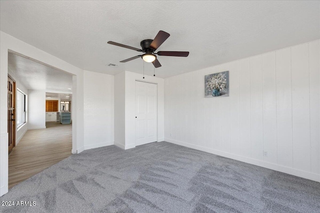 carpeted spare room with ceiling fan and a textured ceiling