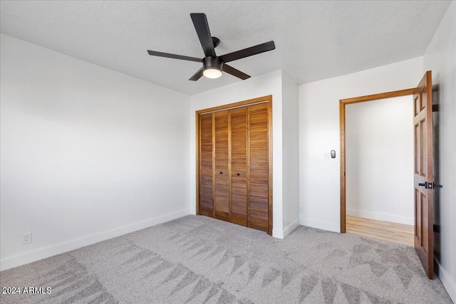 unfurnished bedroom with ceiling fan, a closet, light carpet, and a textured ceiling