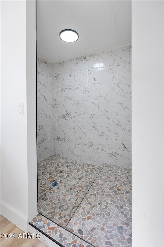 bathroom with tiled shower and hardwood / wood-style floors