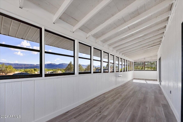 interior space with wood-type flooring, a mountain view, and vaulted ceiling with beams