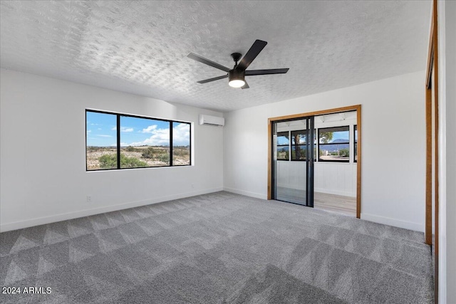 carpeted spare room with ceiling fan, an AC wall unit, and a textured ceiling