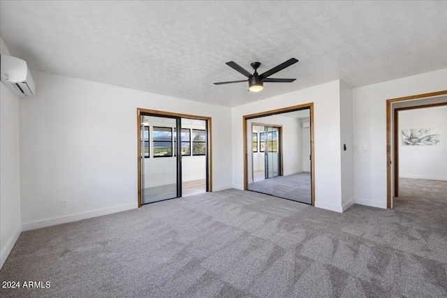 unfurnished bedroom with ceiling fan, a textured ceiling, light colored carpet, and a wall mounted AC