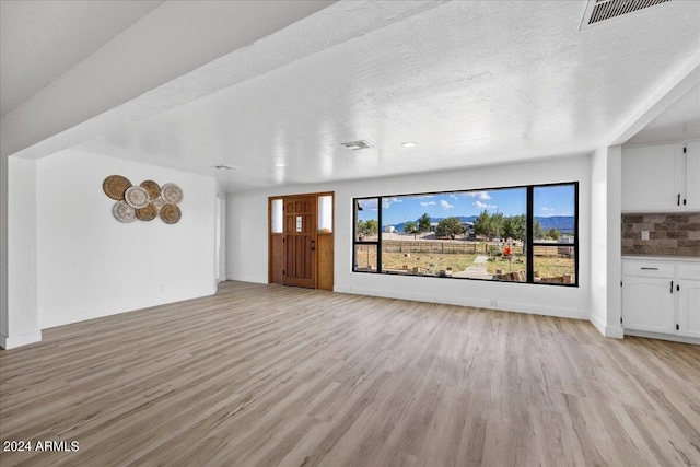 unfurnished living room featuring a textured ceiling and light wood-type flooring