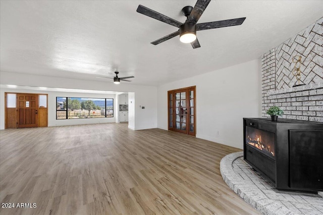 unfurnished living room with ceiling fan, light hardwood / wood-style floors, french doors, and a textured ceiling