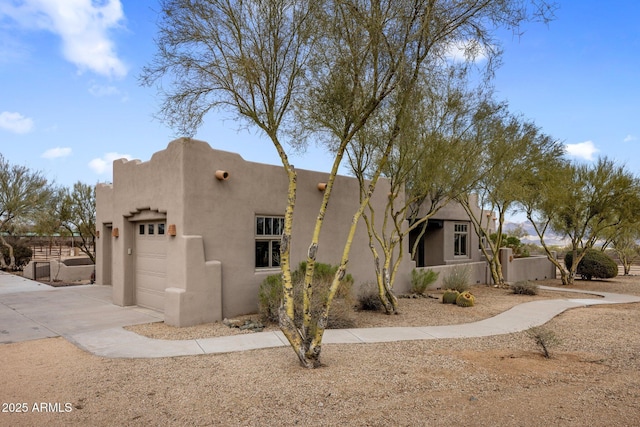 adobe home with a garage, driveway, and stucco siding