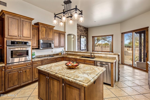 kitchen featuring visible vents, a sink, stainless steel appliances, arched walkways, and a peninsula