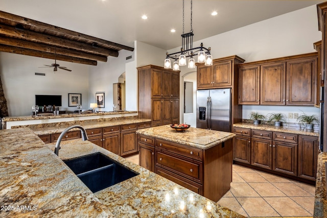 kitchen featuring light stone counters, stainless steel fridge with ice dispenser, arched walkways, a sink, and beamed ceiling