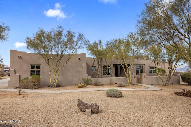 rear view of property featuring a fenced front yard and stucco siding