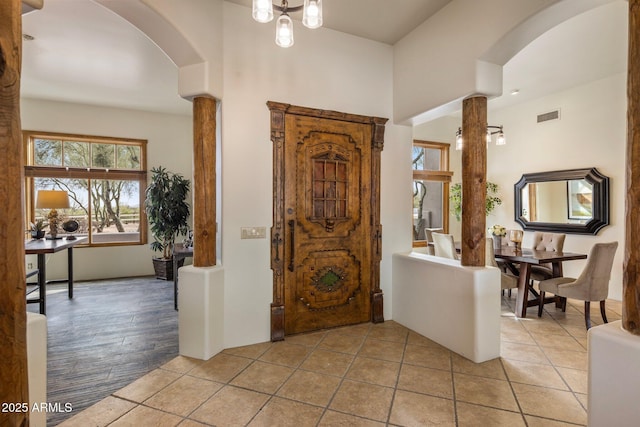 foyer with arched walkways, visible vents, and light tile patterned floors