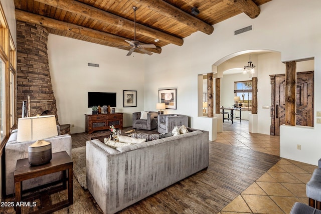 living room with visible vents, arched walkways, beam ceiling, and wooden ceiling