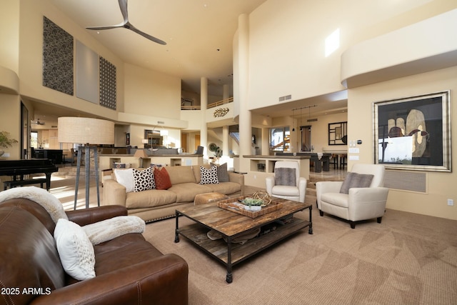 living room with ceiling fan, light carpet, and a high ceiling