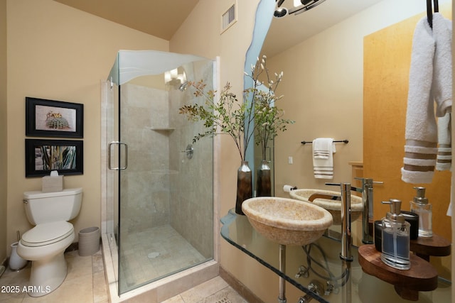 bathroom featuring tile patterned flooring, toilet, and a shower with door