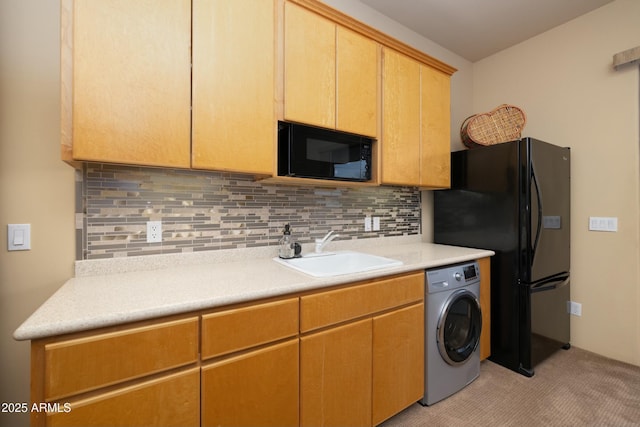 kitchen with backsplash, sink, black appliances, light tile patterned floors, and washer / dryer