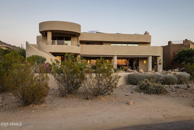 back house at dusk featuring a balcony