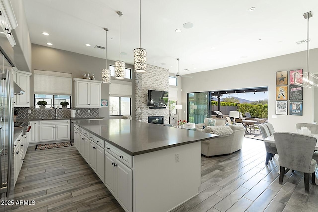 kitchen featuring dark countertops, a center island, decorative backsplash, and wood tiled floor