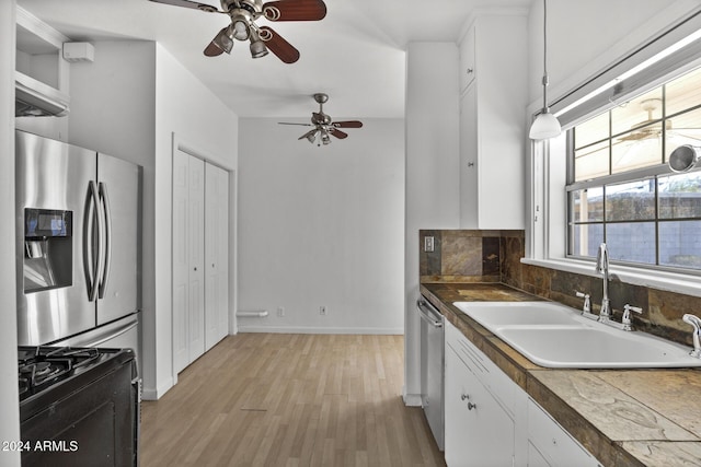 kitchen with appliances with stainless steel finishes, light wood-type flooring, sink, decorative light fixtures, and white cabinets