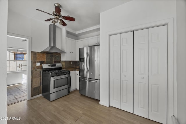 kitchen featuring ceiling fan, white cabinetry, wall chimney exhaust hood, backsplash, and appliances with stainless steel finishes